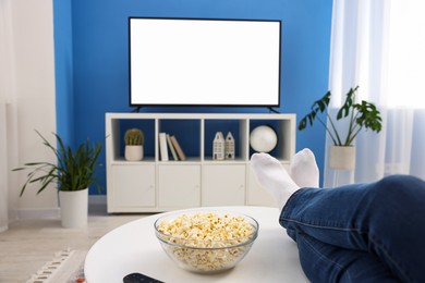 Photo of Woman with popcorn watching tv at home, closeup