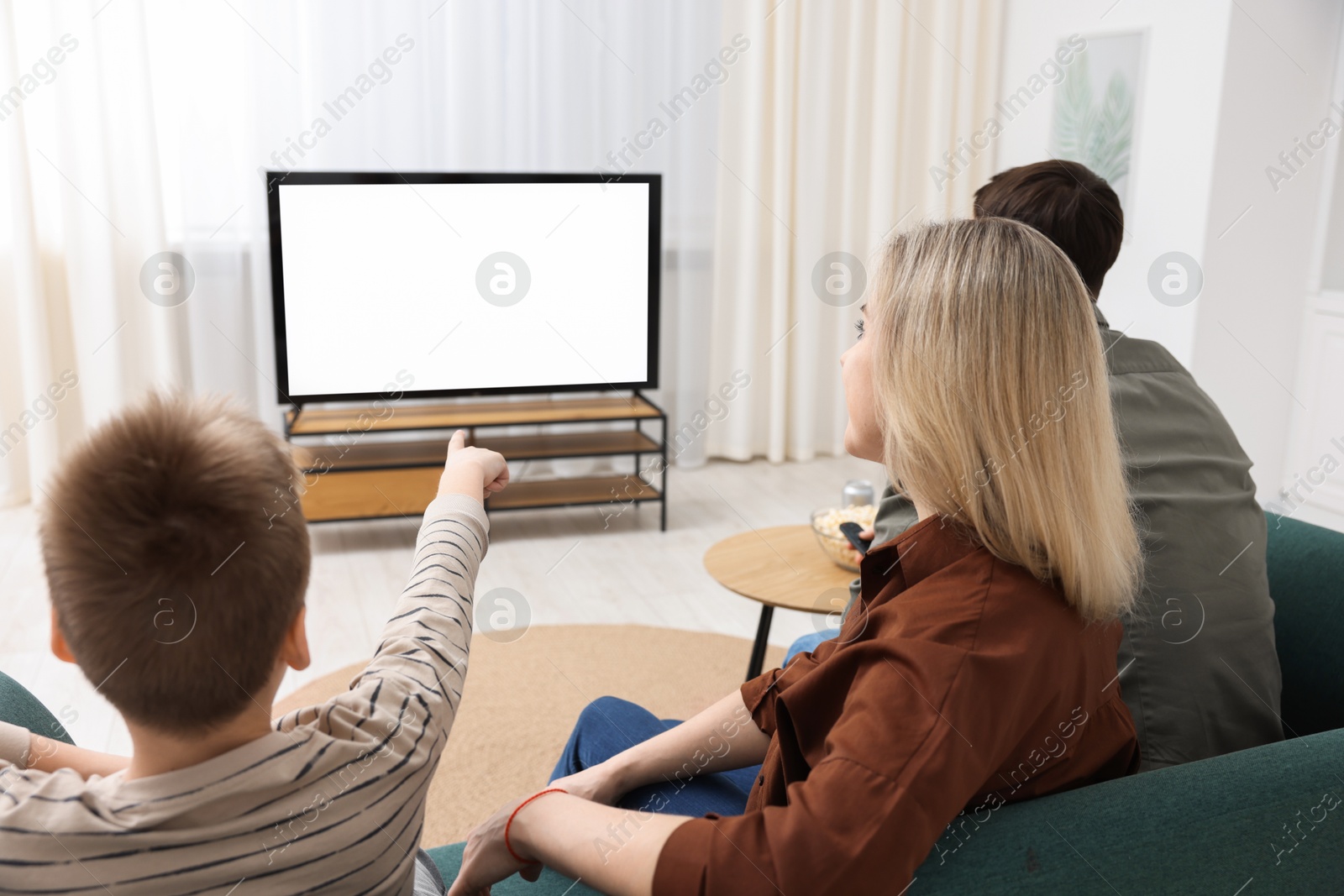 Photo of Happy family watching tv together at home, back view