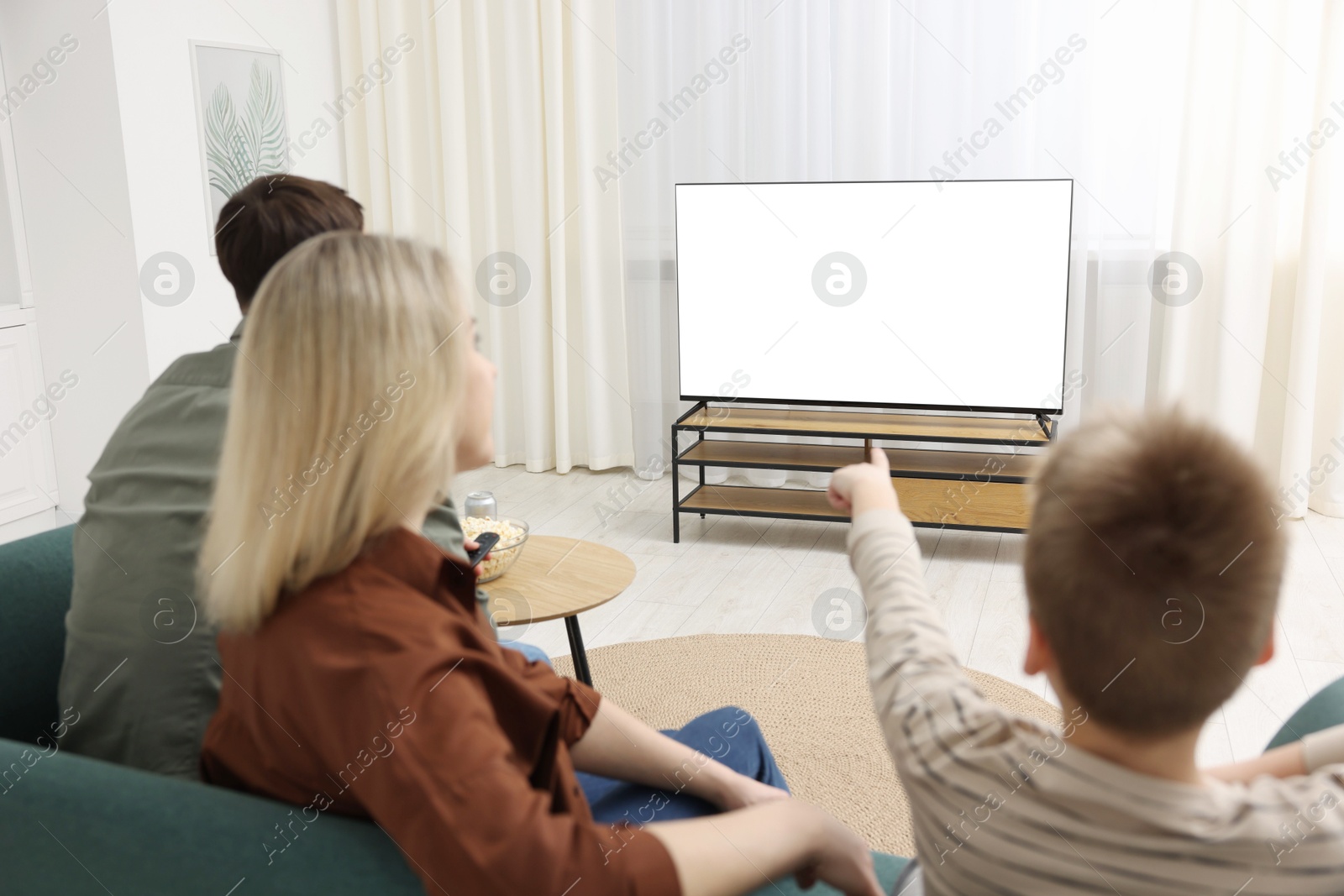 Photo of Happy family watching tv together at home, back view