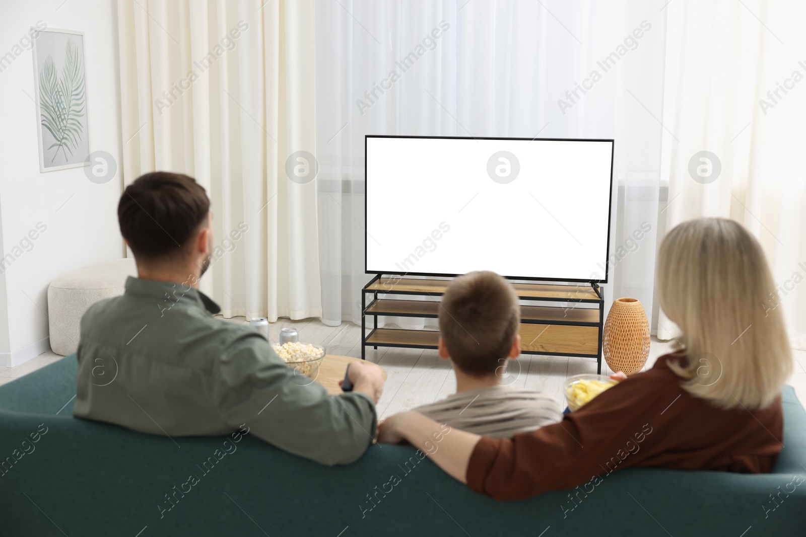 Photo of Happy family watching tv together at home, back view