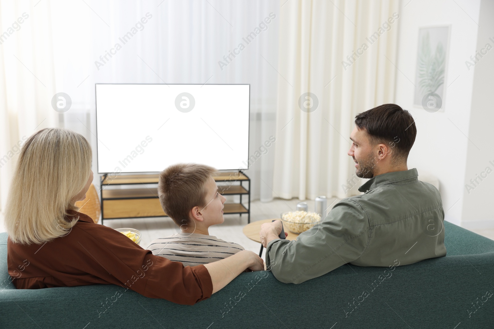 Photo of Happy family watching tv together at home, back view