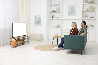 Photo of Lovely couple watching tv on couch at home