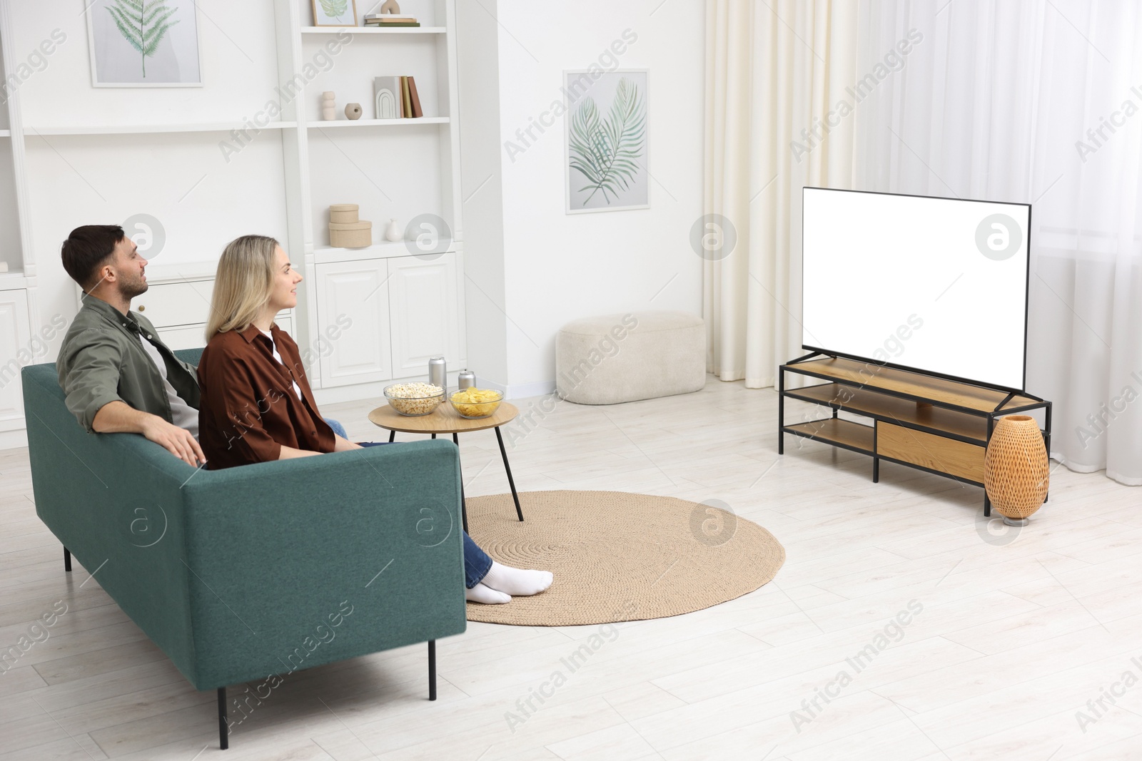 Photo of Lovely couple watching tv on couch at home