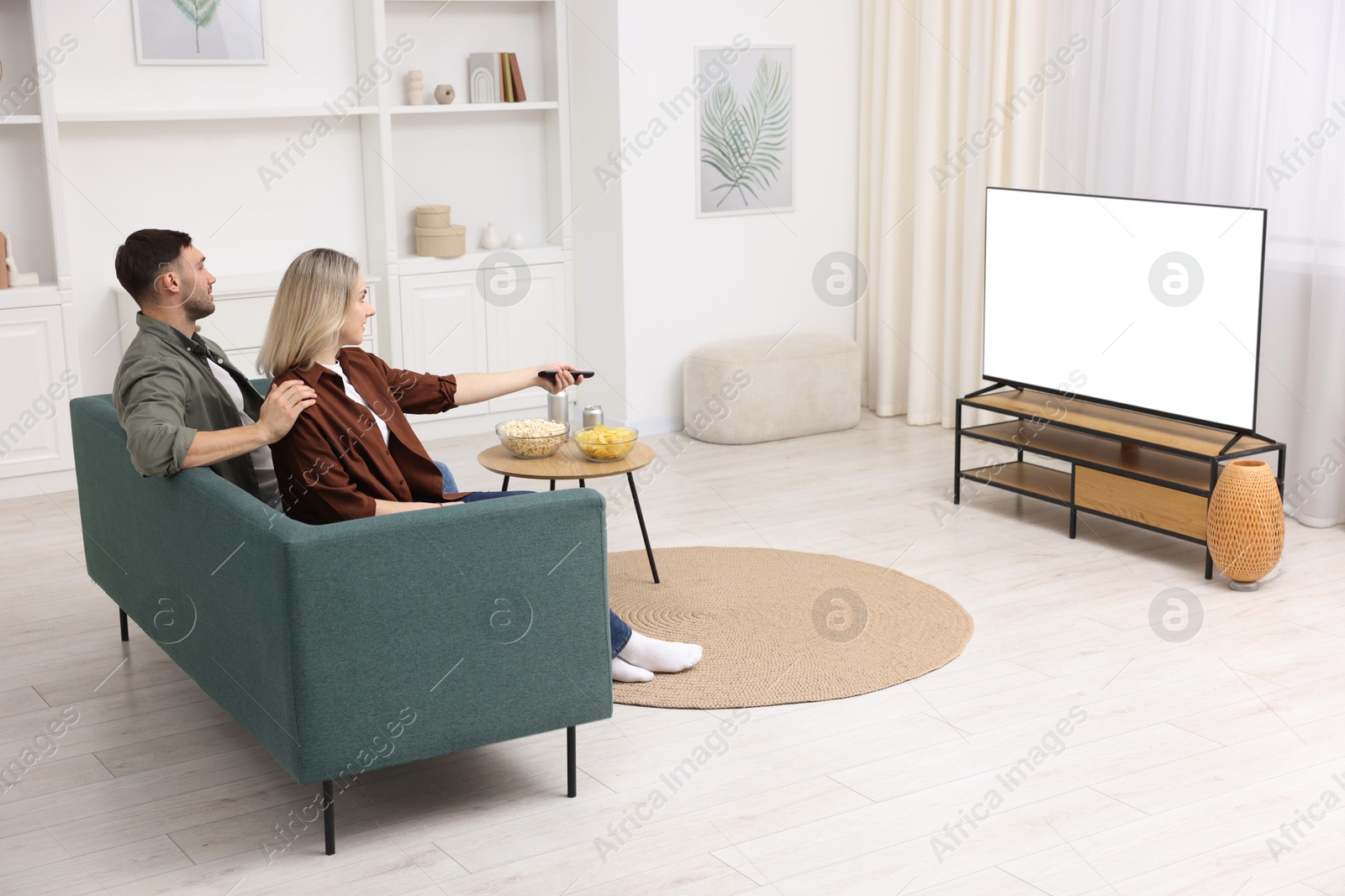 Photo of Lovely couple watching tv on couch at home