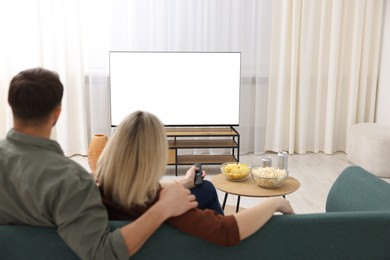 Photo of Lovely couple watching tv on couch at home, back view