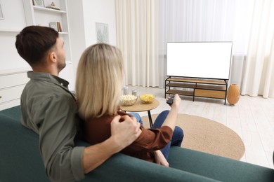 Photo of Lovely couple watching tv on couch at home, back view