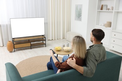 Photo of Lovely couple watching tv on couch at home