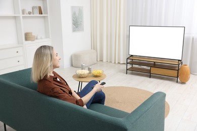 Woman with snacks and drinks watching tv on couch at home