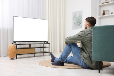 Photo of Man watching tv on floor at home