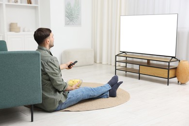 Photo of Man with chips watching tv on floor at home