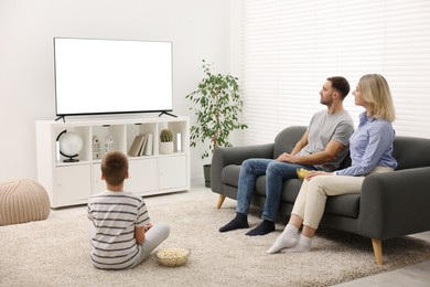 Happy family with snacks watching tv together at home