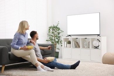 Photo of Lovely couple with snacks watching tv at home