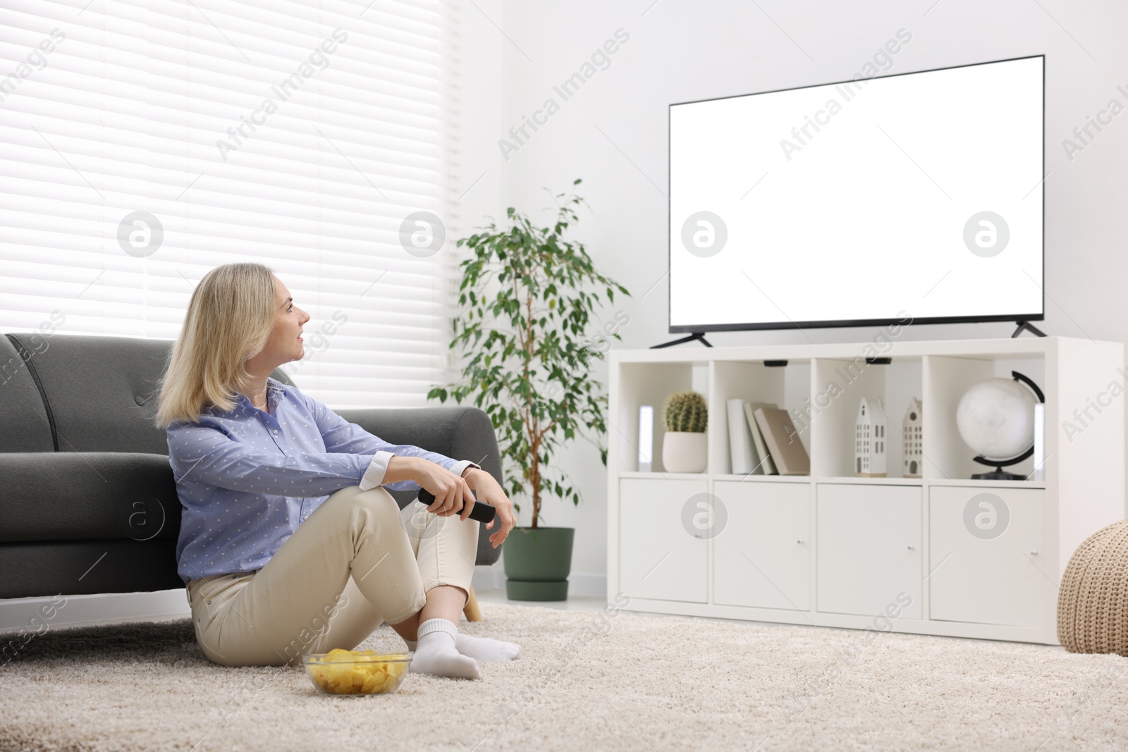 Photo of Woman with chips watching tv at home