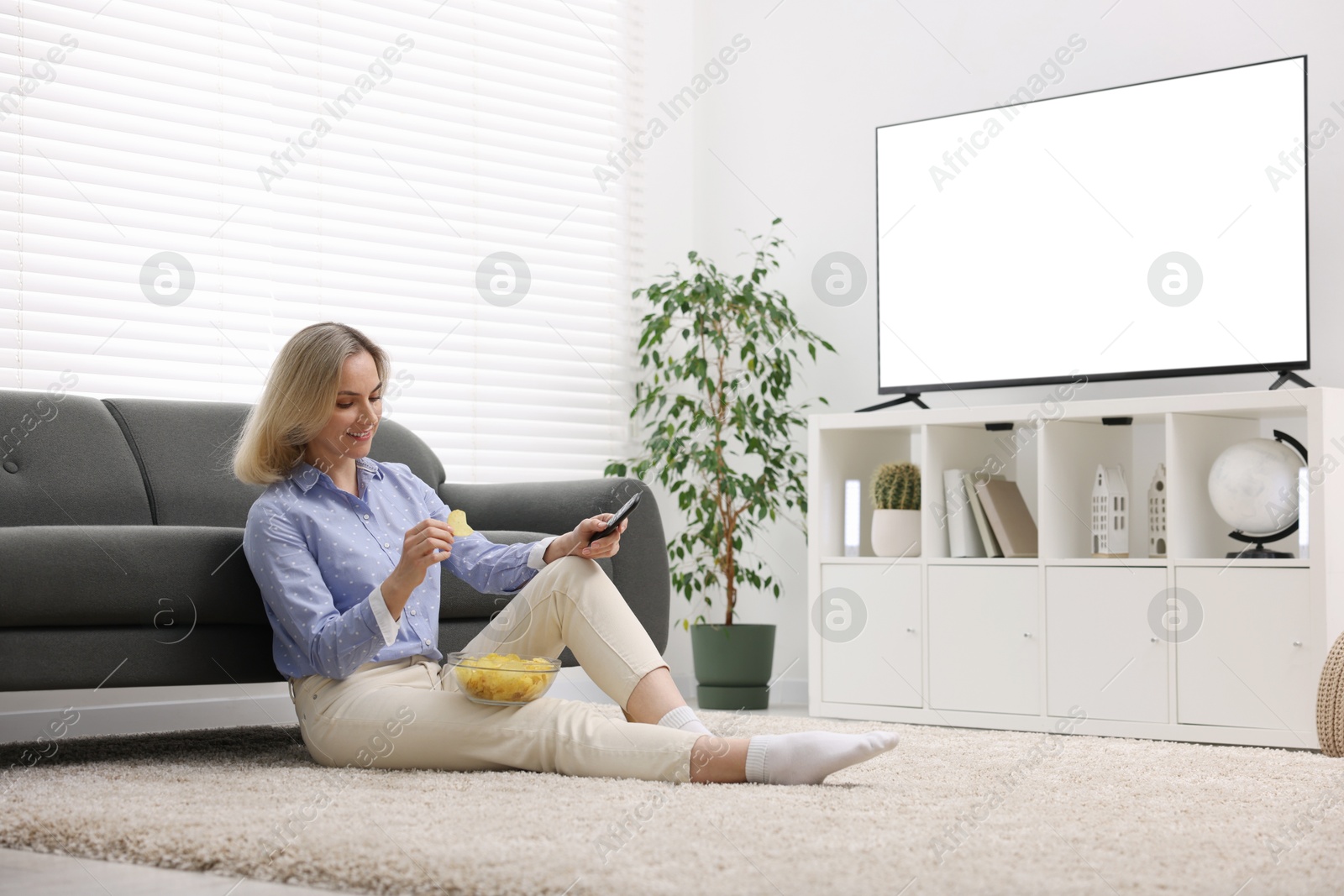 Photo of Woman with chips watching tv at home