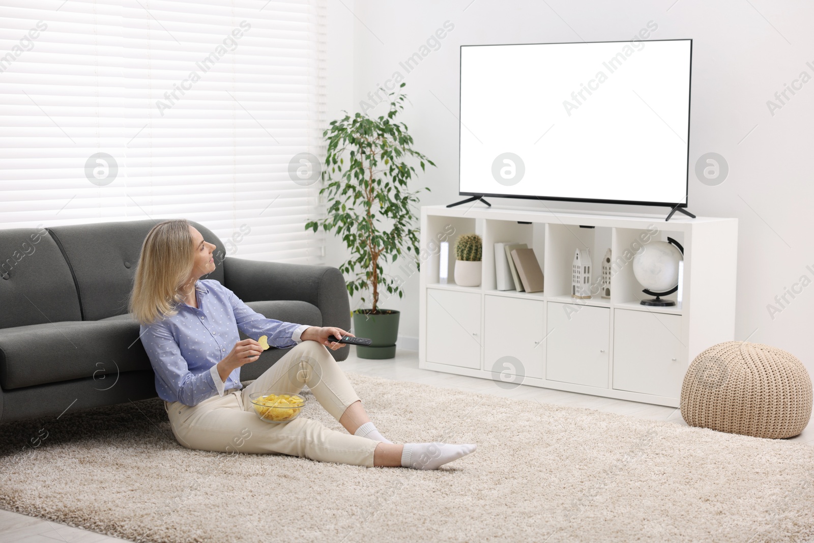 Photo of Woman with chips watching tv at home