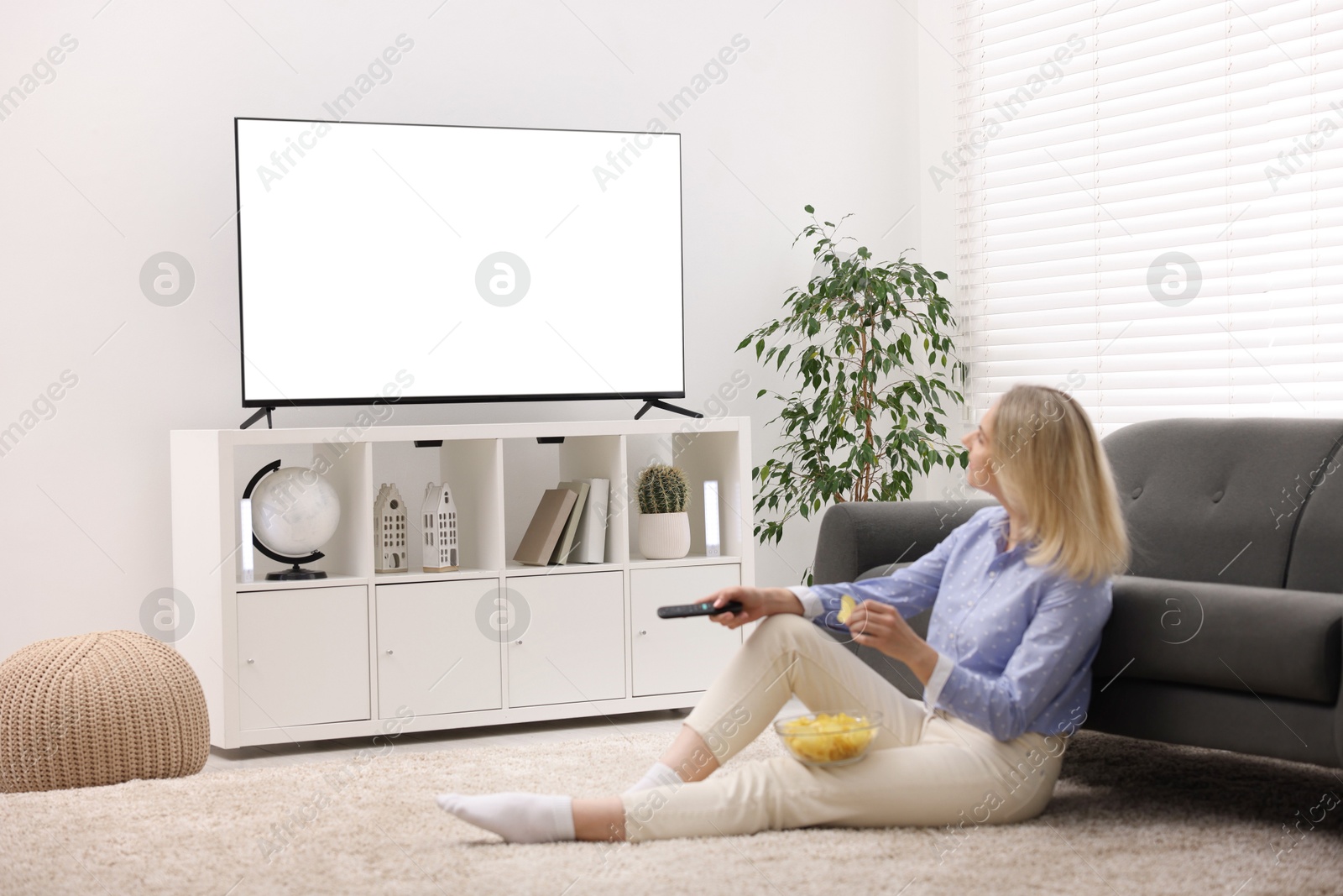 Photo of Woman with chips watching tv at home