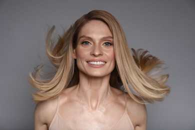 Photo of Portrait of beautiful happy woman with straight blonde hair on grey background