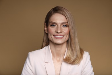 Photo of Portrait of beautiful happy woman with straight blonde hair on light brown background