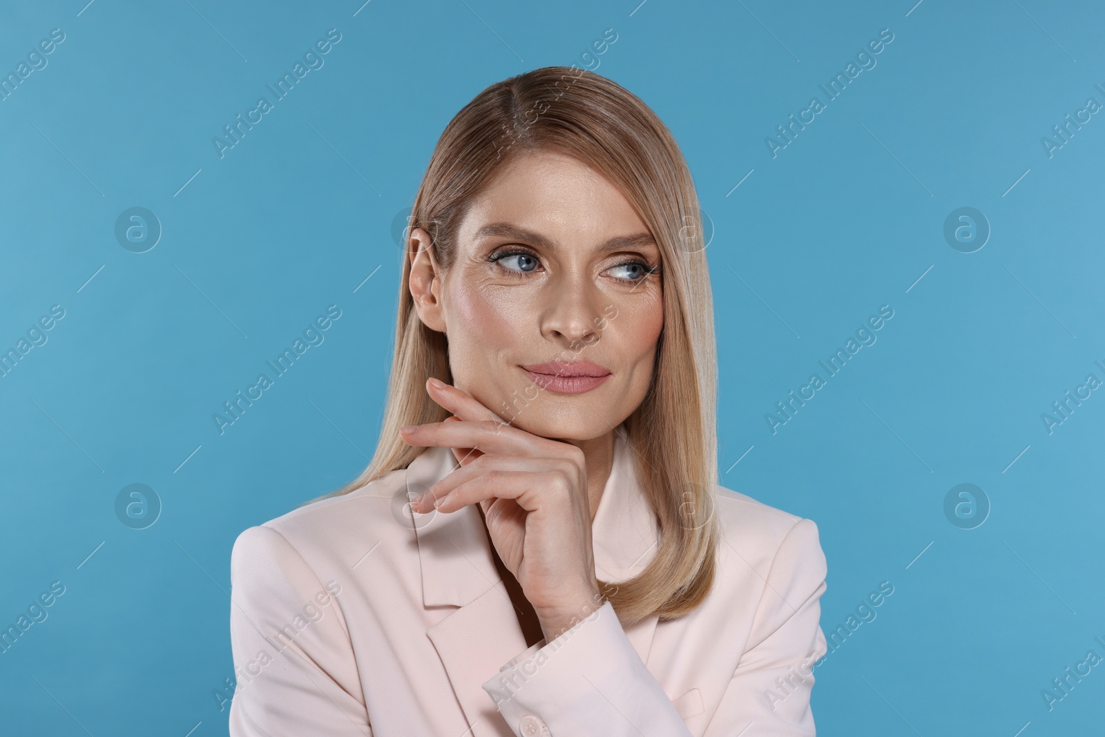 Photo of Portrait of beautiful woman with straight blonde hair on light blue background