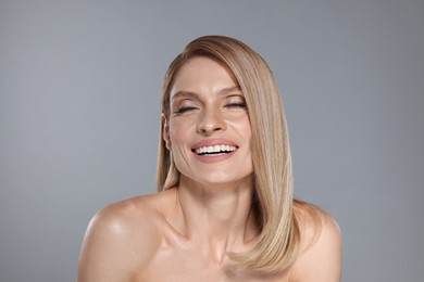 Photo of Portrait of beautiful happy woman with straight blonde hair on grey background