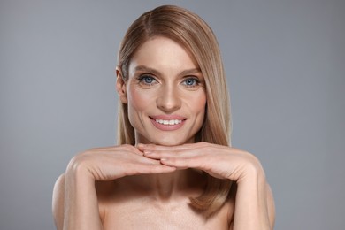 Photo of Portrait of beautiful happy woman with straight blonde hair on grey background