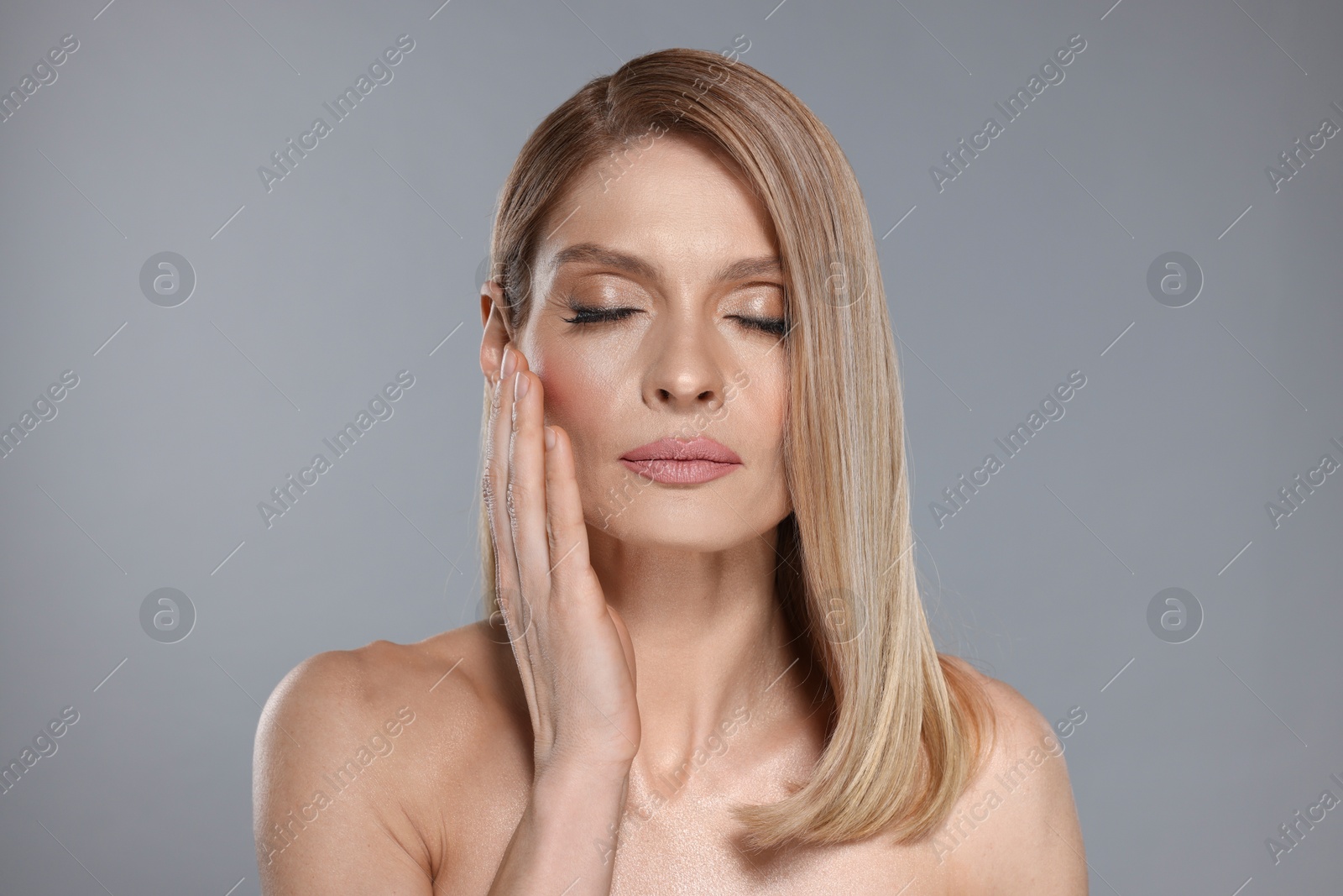 Photo of Portrait of beautiful woman with straight blonde hair on grey background