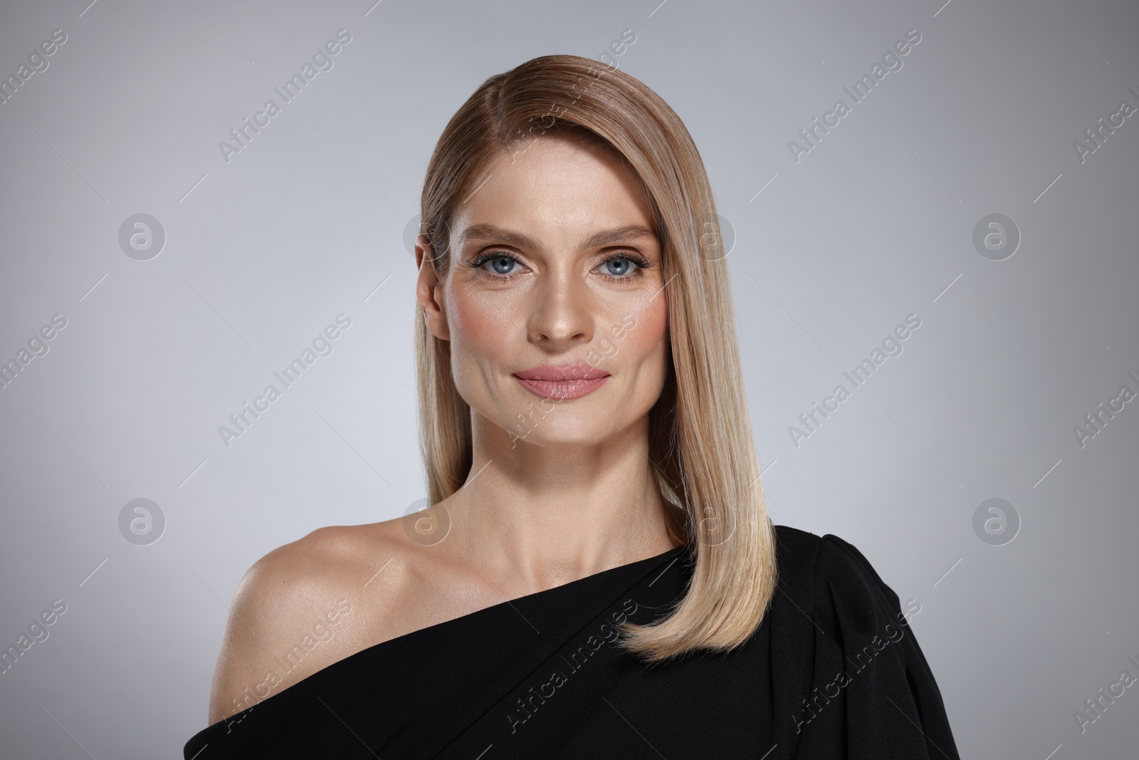 Photo of Portrait of beautiful woman with straight blonde hair on grey background