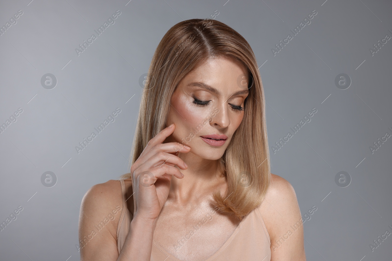 Photo of Portrait of beautiful woman with straight blonde hair and stylish makeup on light grey background