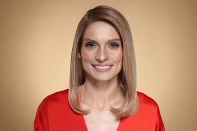 Portrait of beautiful happy woman with straight blonde hair on beige background