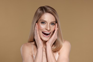 Photo of Portrait of beautiful happy woman with straight blonde hair on beige background