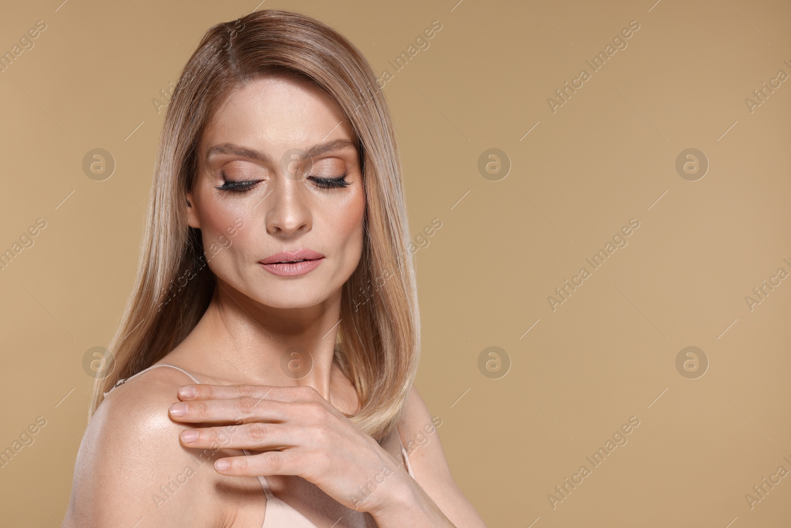 Photo of Portrait of beautiful woman with straight blonde hair and stylish makeup on beige background, space for text