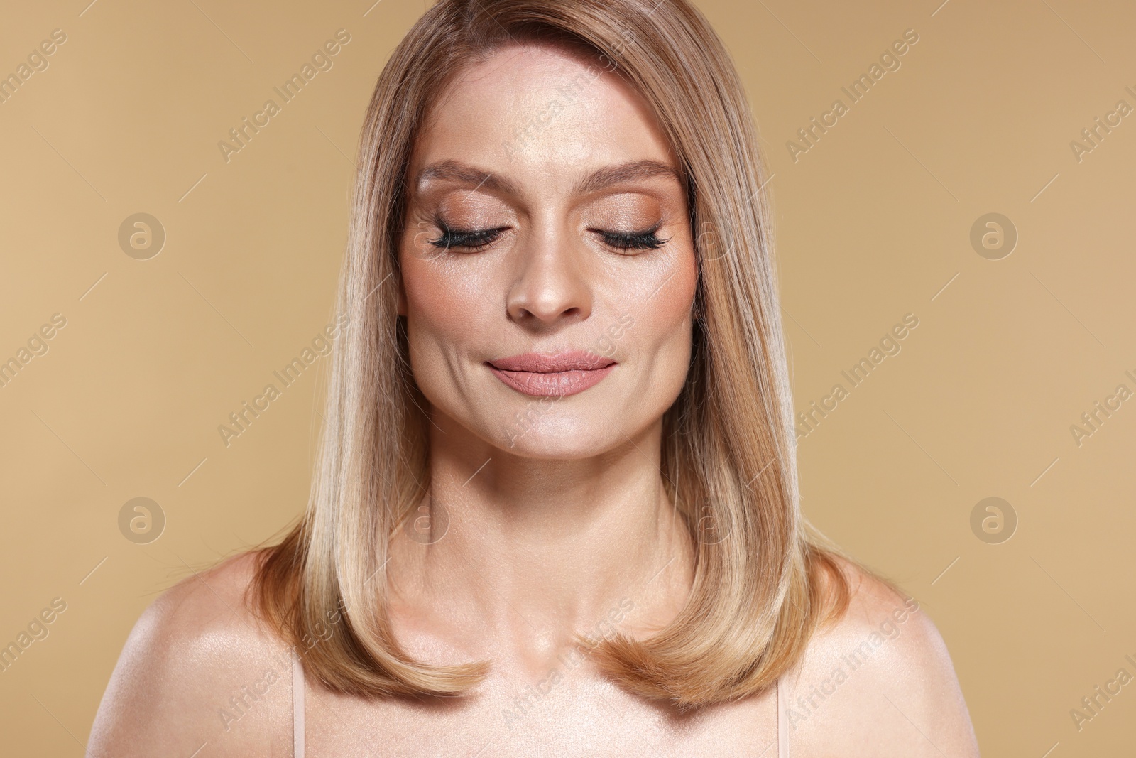 Photo of Portrait of beautiful woman with straight blonde hair and stylish makeup on beige background