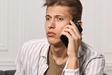 Photo of Worried man calling hotline for mental health help at home