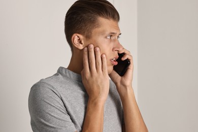 Photo of Stressed man calling hotline for mental health help indoors