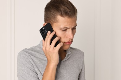 Photo of Frustrated man calling hotline for mental health help indoors