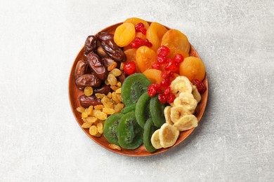 Photo of Mix of different dried fruits in bowl on light grey table, top view