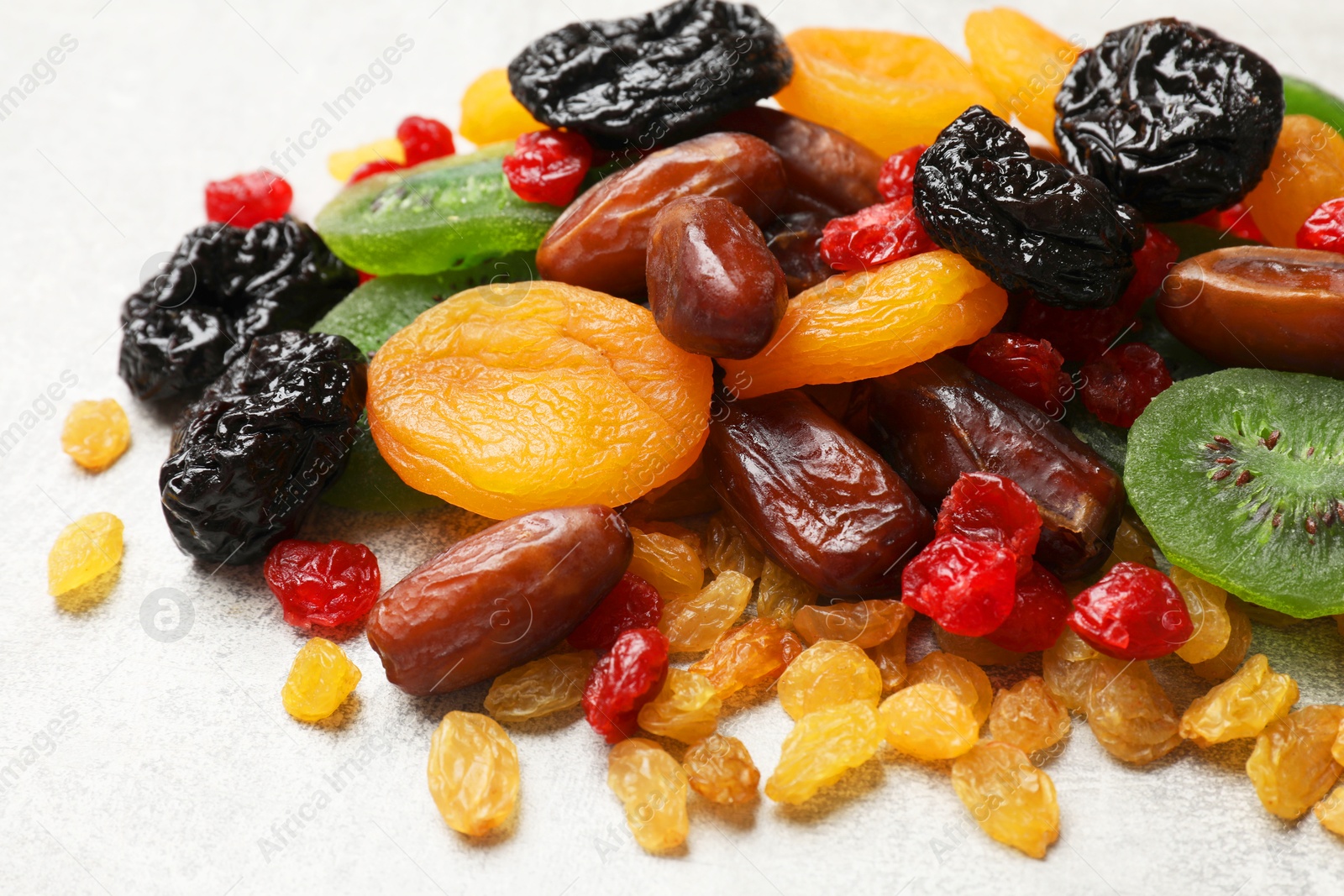 Photo of Mix of different dried fruits on light grey table, closeup