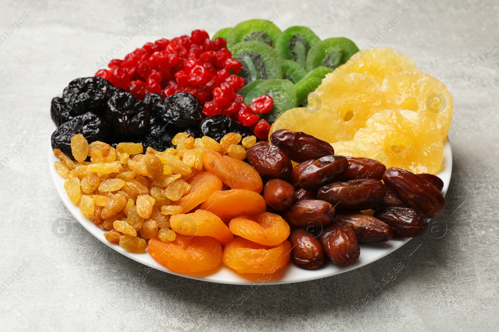 Photo of Mix of different dried fruits on gray textured table, closeup