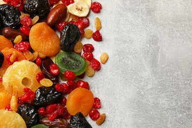 Photo of Mix of different dried fruits on gray textured table, top view. Space for text