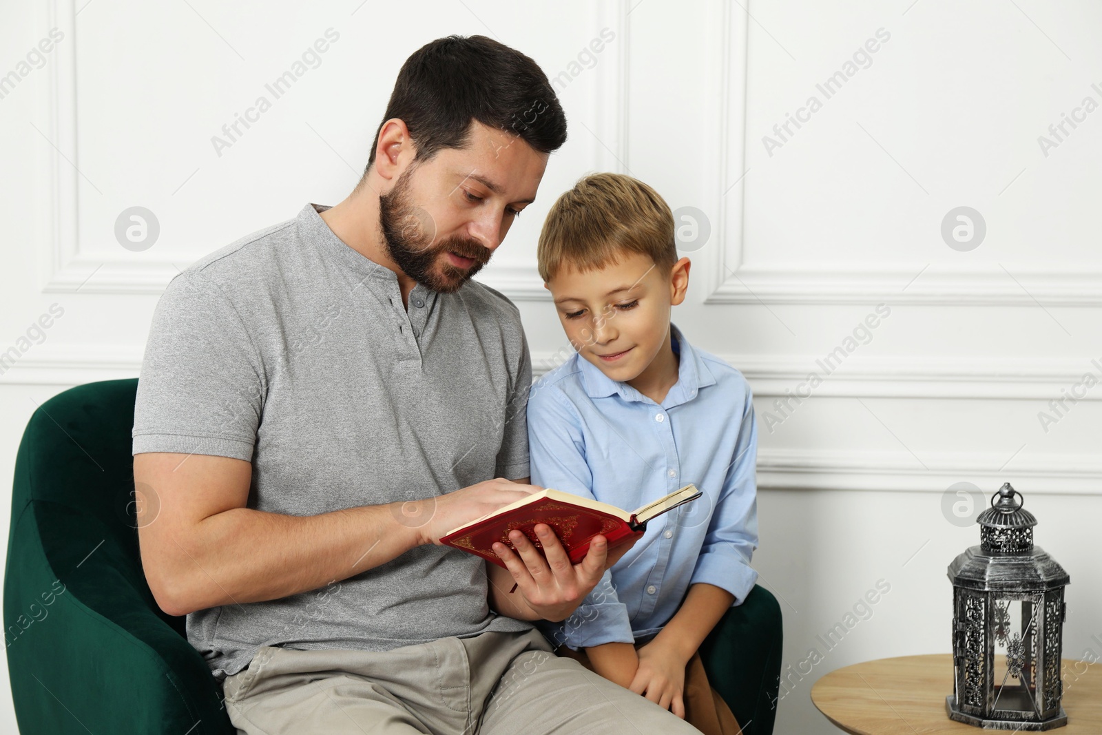 Photo of Muslim man and his son reading Quran at home