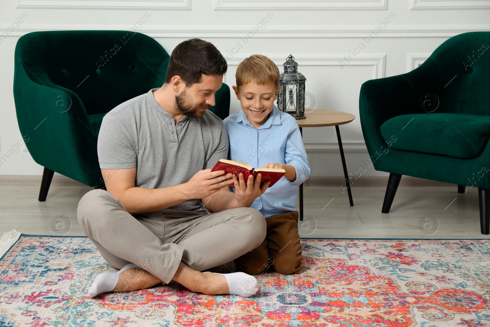 Photo of Muslim man and his son reading Quran at home