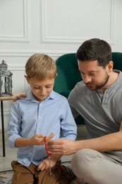 Photo of Muslim man and his son with prayer beads at home