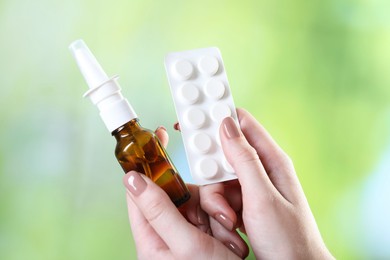 Photo of Allergy treatment. Woman with nasal spray and pills on blurred background, closeup