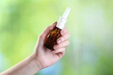 Photo of Allergy treatment. Woman with nasal spray on blurred background, closeup