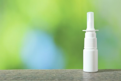 Photo of Allergy treatment. Nasal spray on wooden table against blurred background. Space for text