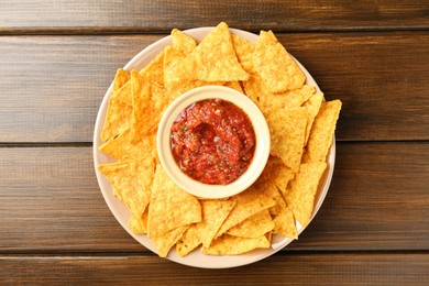 Photo of Delicious salsa with nachos on wooden table, top view