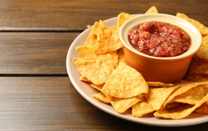 Photo of Delicious salsa with nachos on wooden table, closeup. Space for text