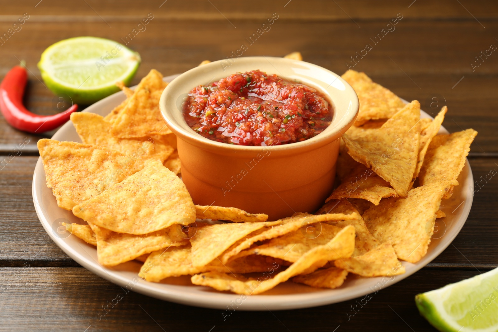 Photo of Delicious salsa with nachos on wooden table, closeup