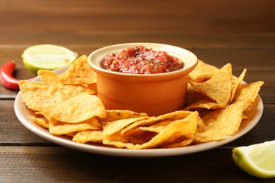 Photo of Delicious salsa with nachos on wooden table, closeup