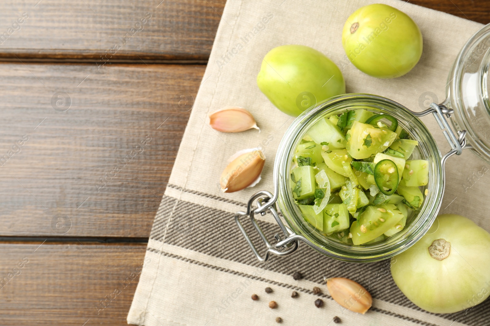 Photo of Delicious green salsa in jar and ingredients on wooden table, flat lay. Space for text